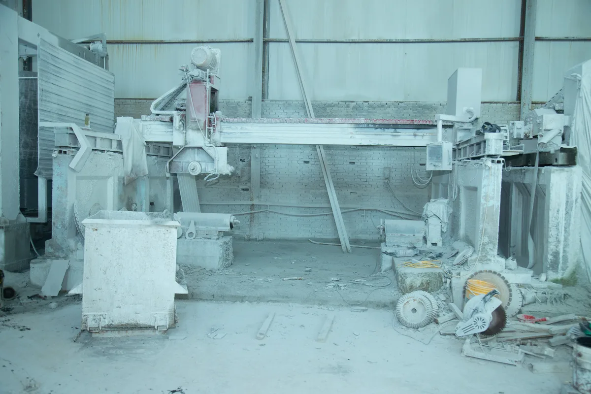 Interior of a stone sculpture factory with heavy-duty cutting and processing machines.