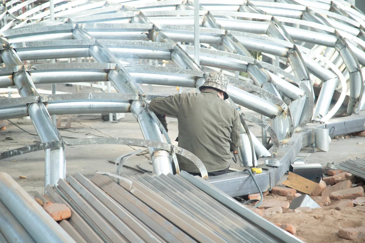 Welding work on a large stainless steel sculpture structure in the factory workshop.