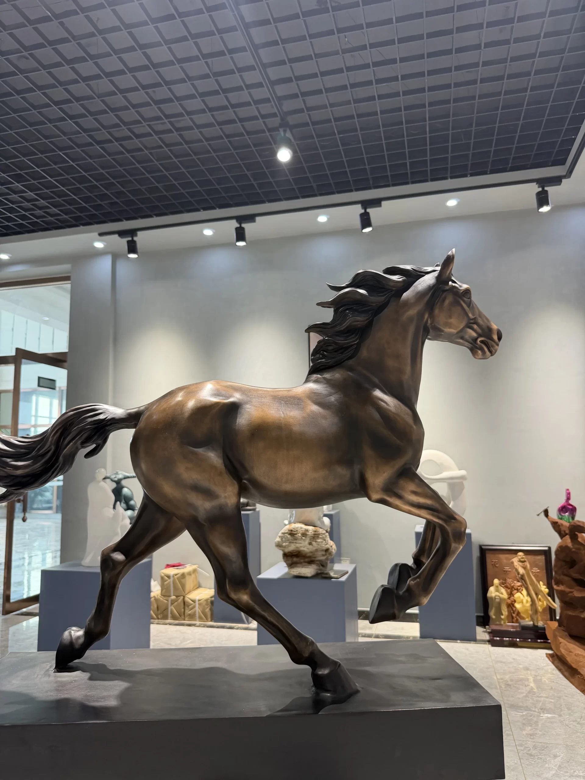 Finished bronze horse sculpture with a dark brown surface under gallery lighting
